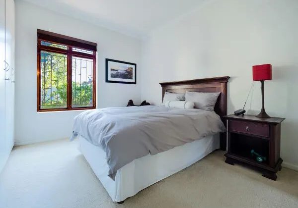 A bedroom with a bed, nightstand and window.
